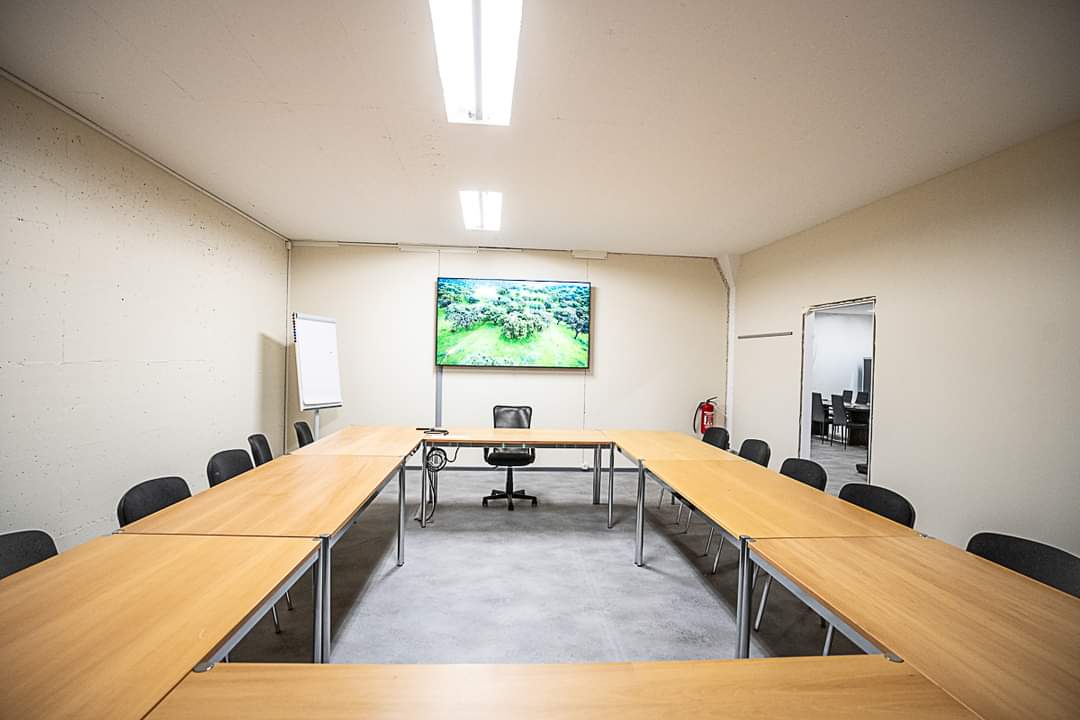 Eventraum von Shooting Point mit U-förmiger Tischanordnung und Präsentationsbildschirm